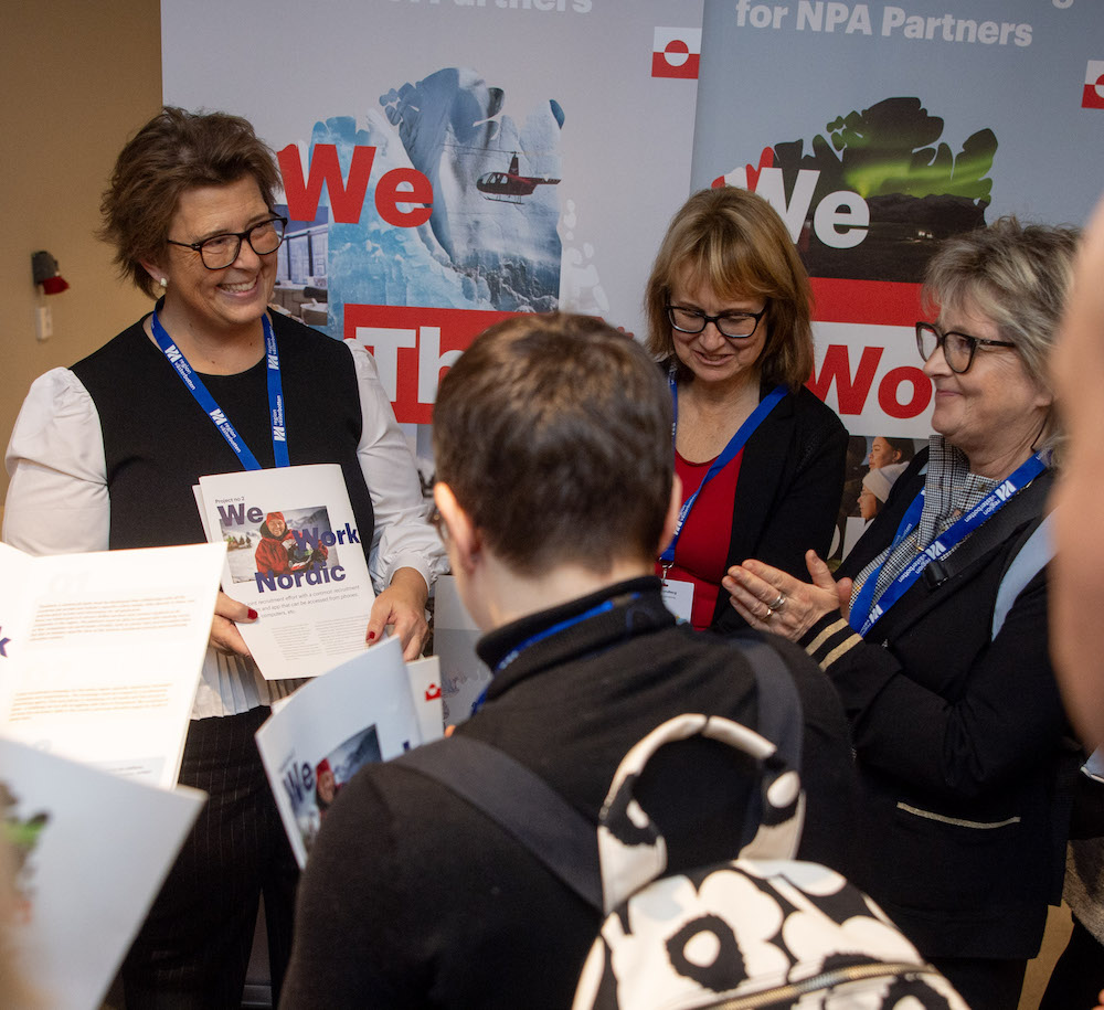Lady presenting a leaflet about cooperation in Greenland to an interested audience